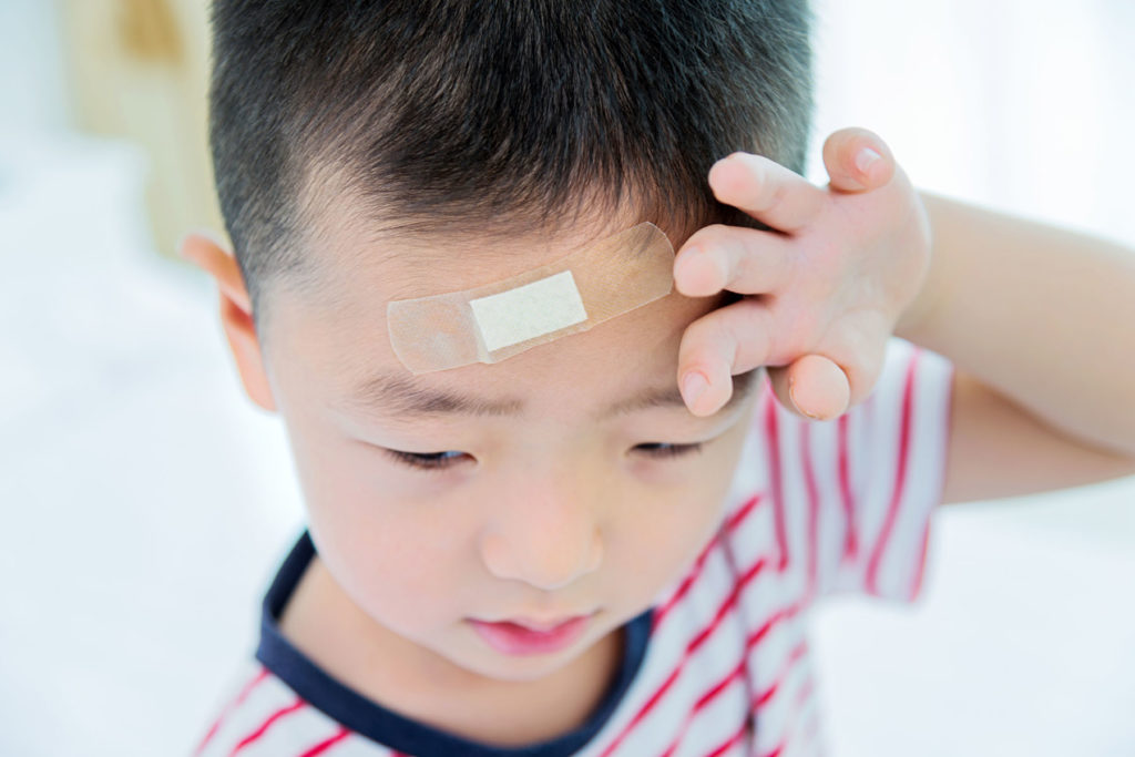 Young Asian boy with bandaid on head