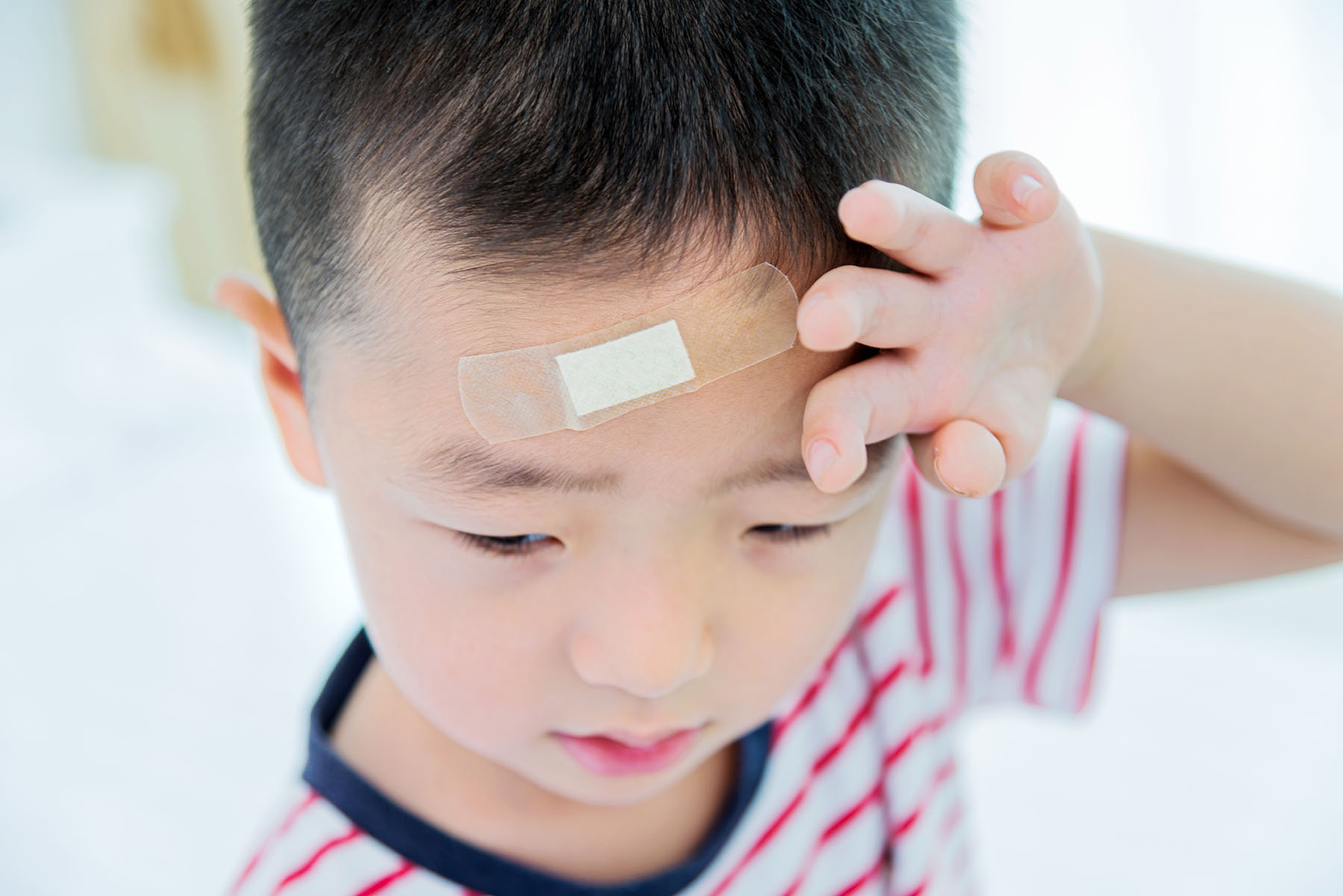 Young Asian boy with bandaid on head