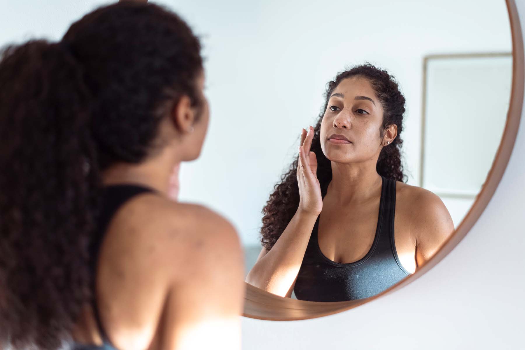 Adult woman inspecting face in mirror
