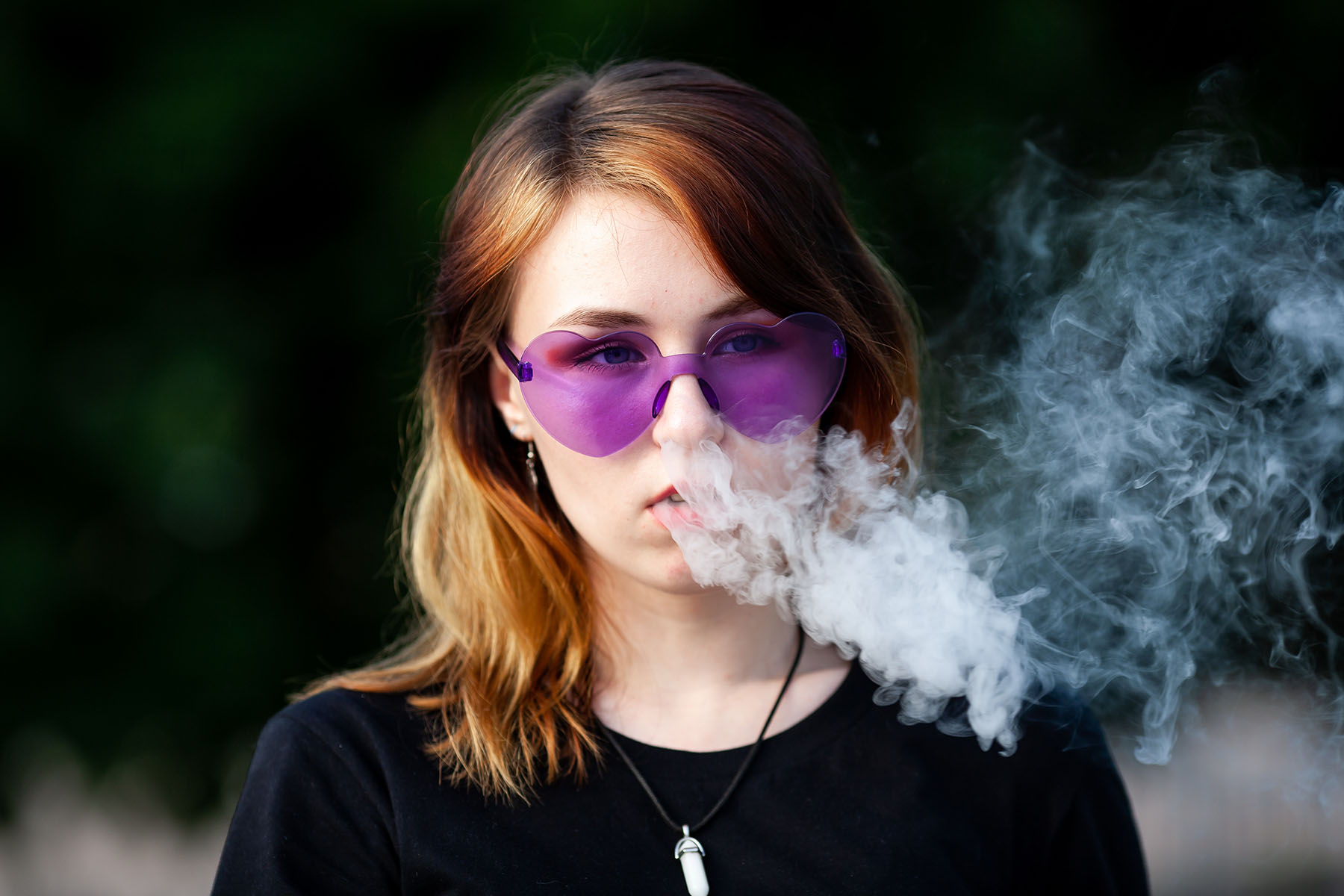 Teen girl with purple glasses vapes