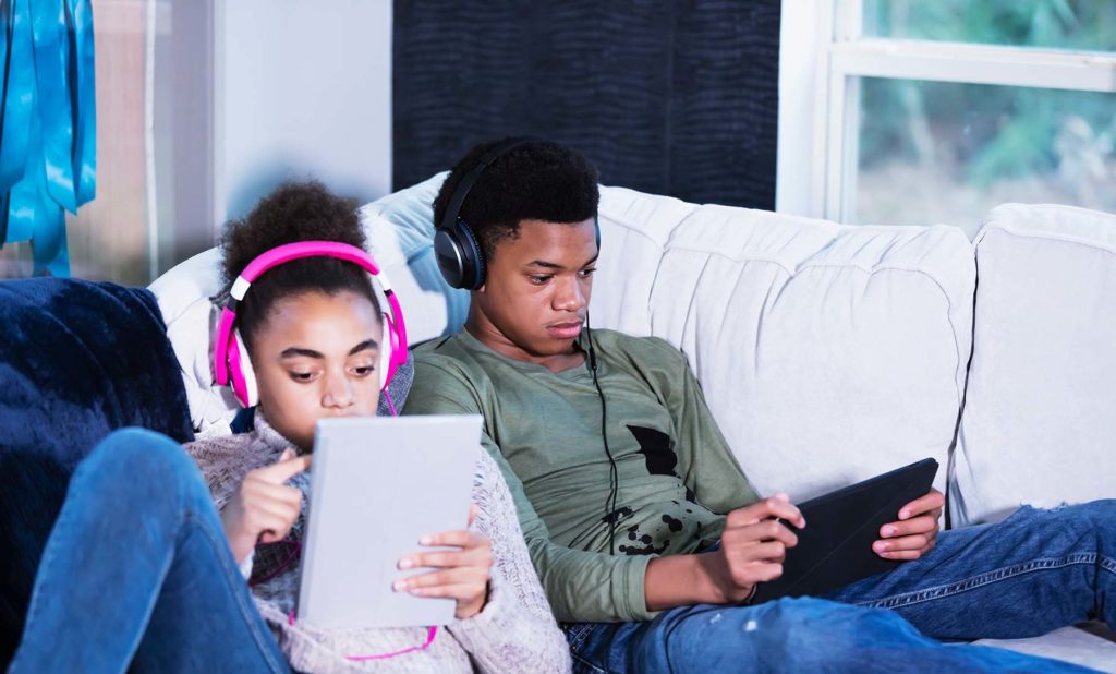 Brother and sister on couch looking at screens