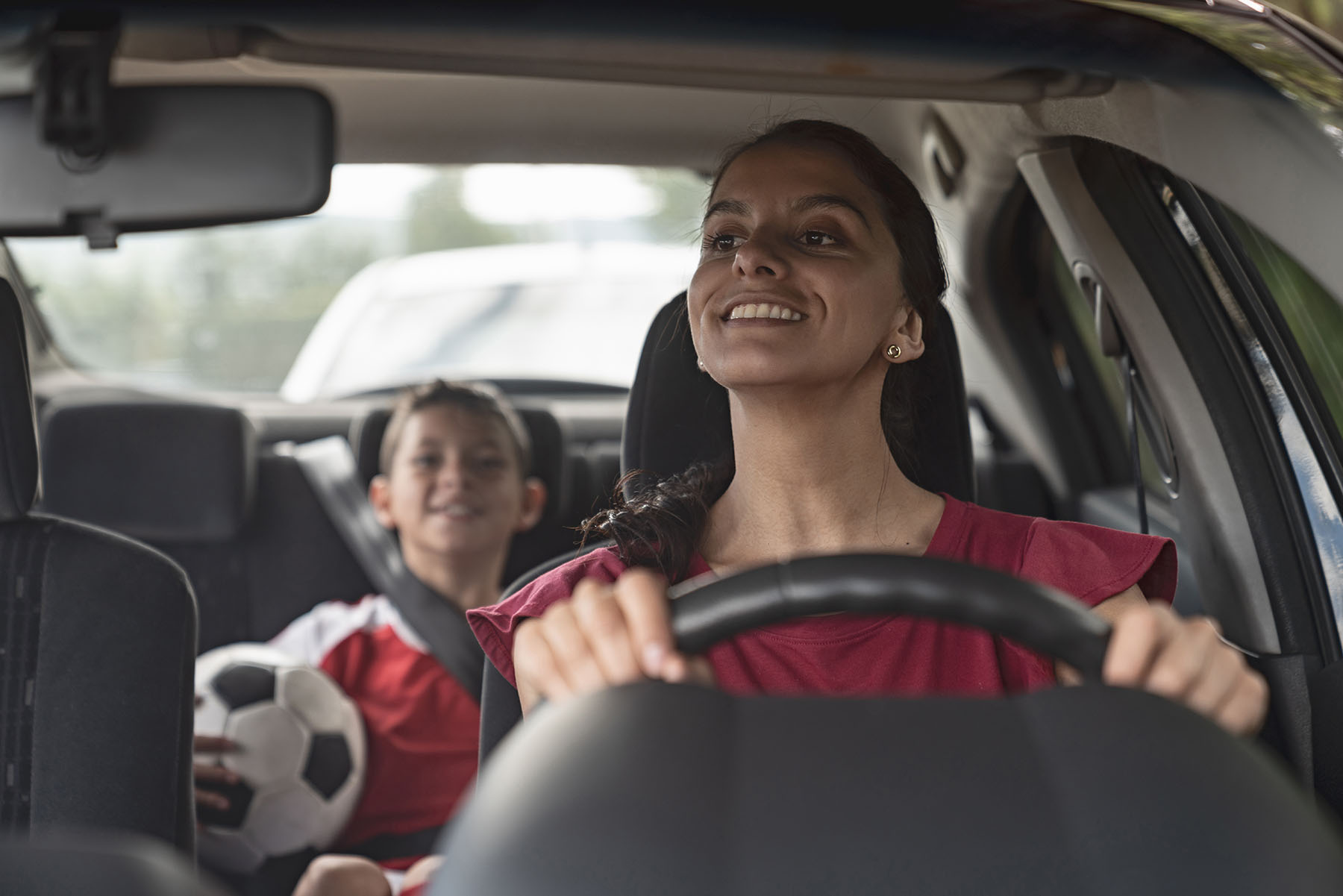 Happy Hispanic mom drives young boy to soccer