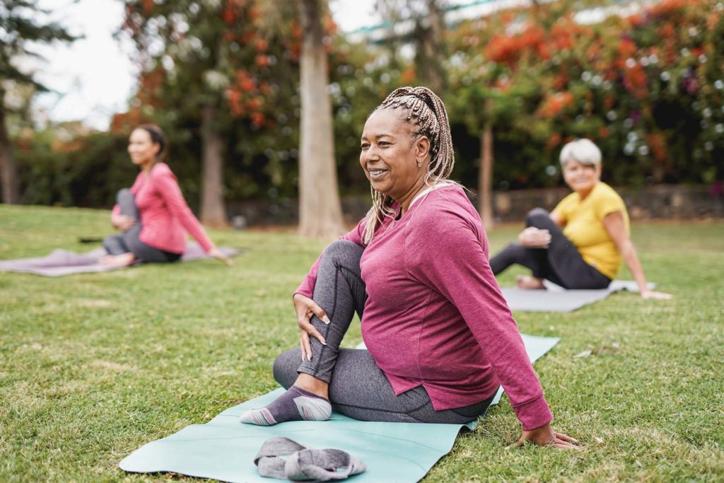 Older women doing yoga in a grassy park