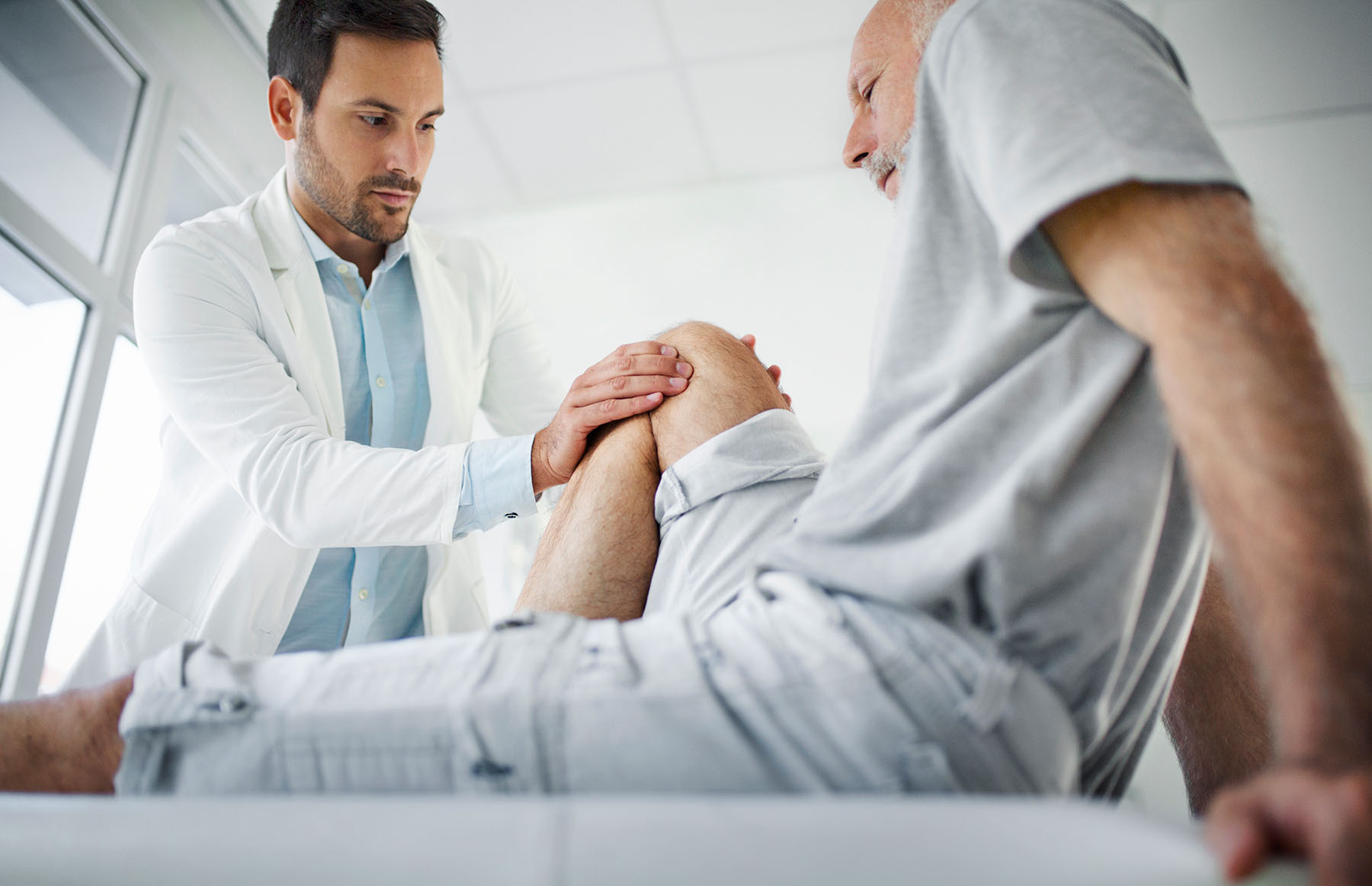 Doctor check's elder male patient's knee
