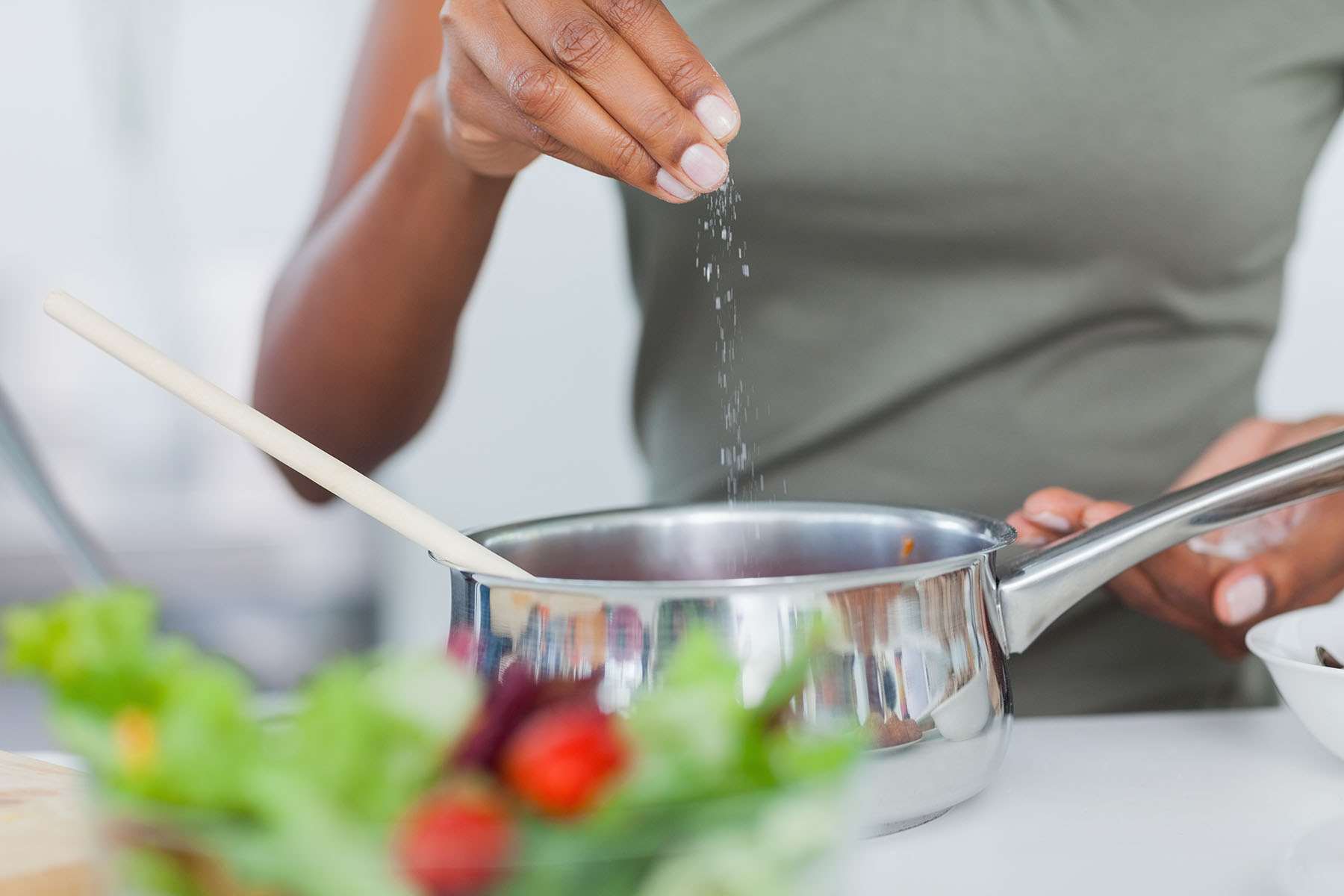 Black woman adds salt to pan