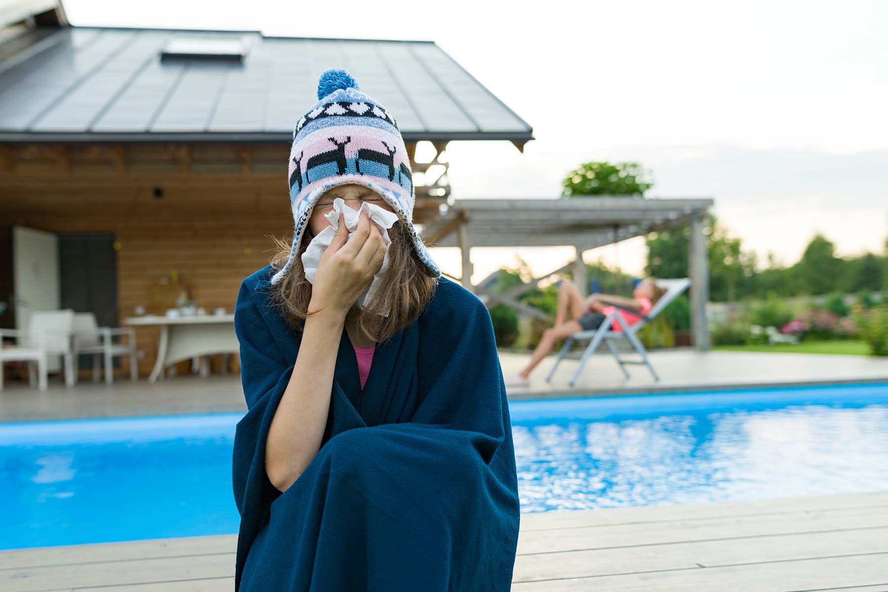 Girl sneezing by pool. Vacation health theme