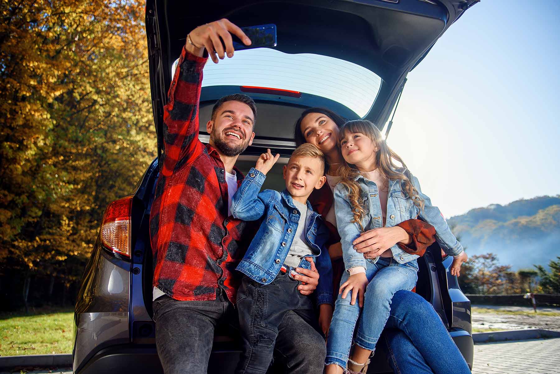 Cute family on roadtrip taking a selfie in the back of the car.