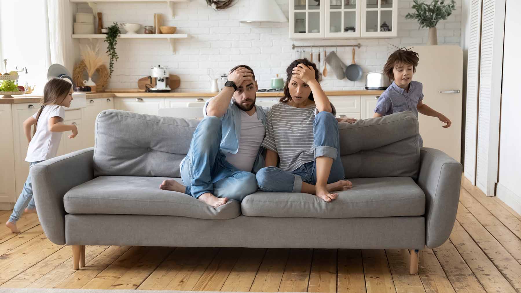 Stressed parents on couch, kids run wild