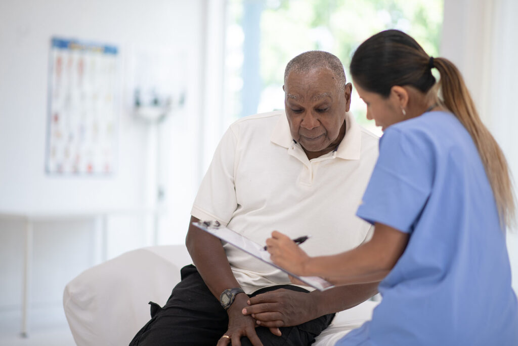 Black older man talks to doctor about test results on his prostate exam.