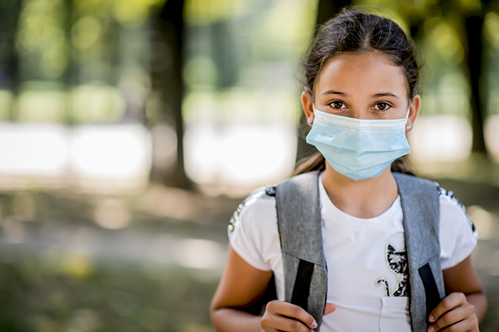 Portrait of girl going to school with protective face mask on.
