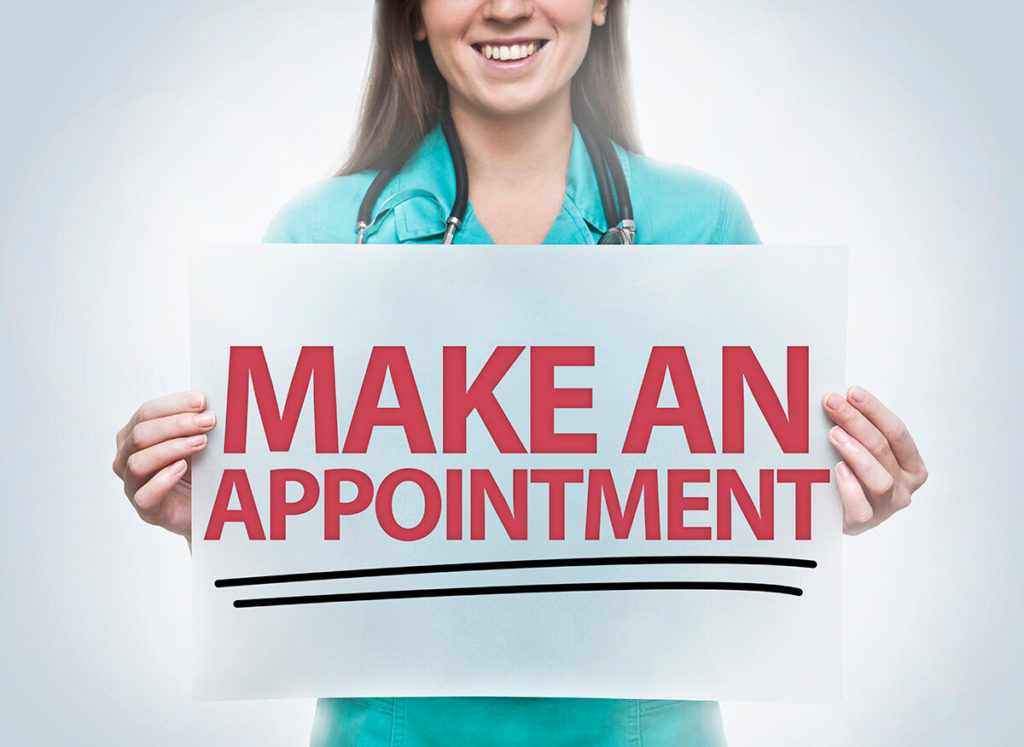 Woman in nurse uniform holds Make an Appointment sign