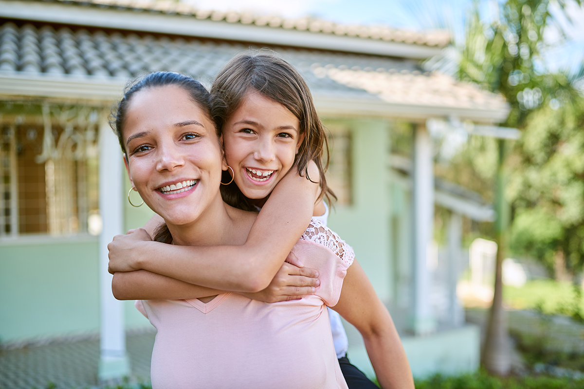 Portrait of a happy mother and daughter playing together in their backyard