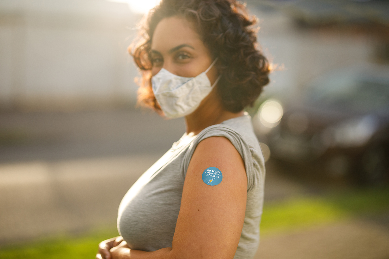 Young Hispanic woman in COVID mask with vaccination sticker