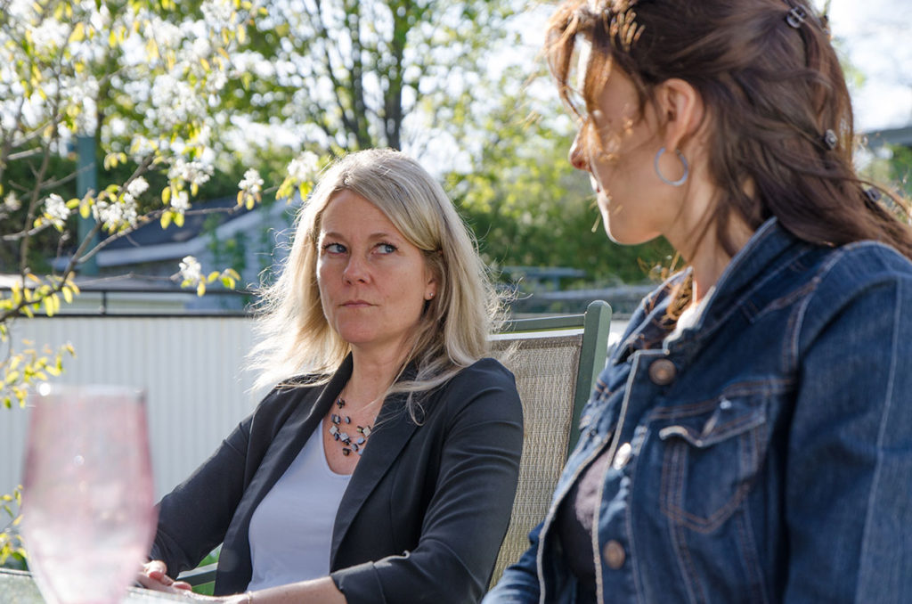 Woman sits outside looking grimly at woman next to her