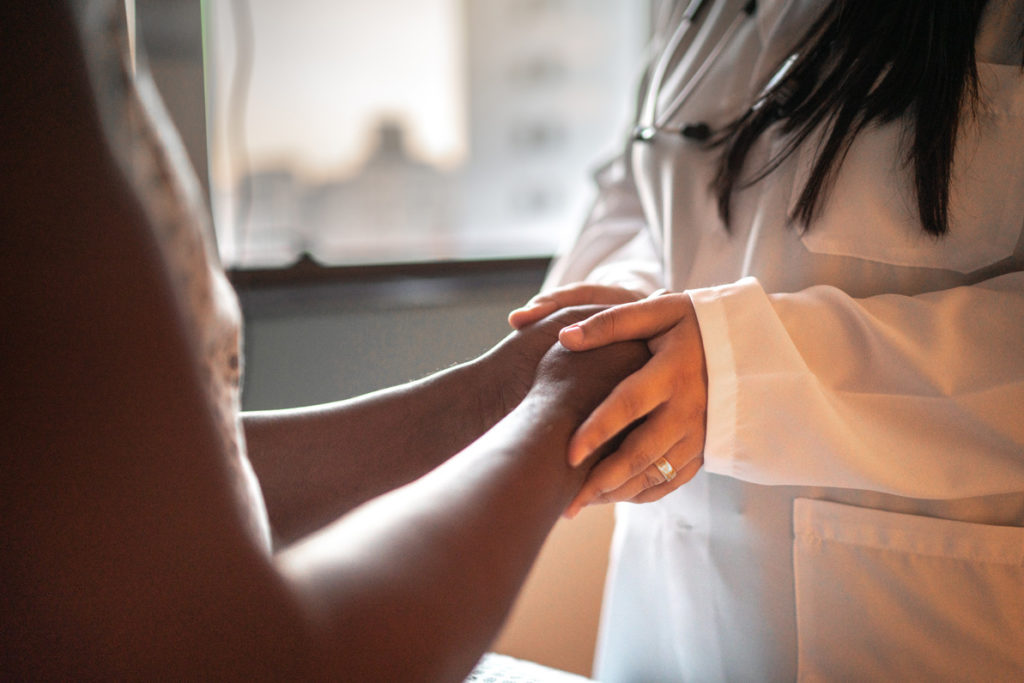 Close up of physician clasping hands with Black woman patient