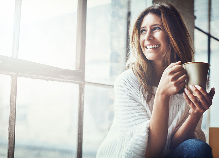 Woman sits in window with tea