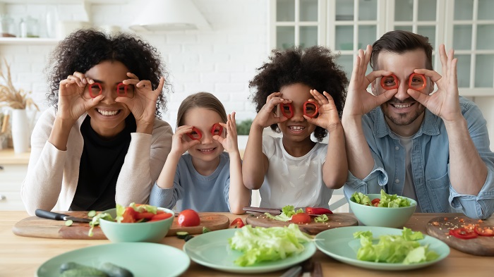 Cute kids at a table covering eyes with red paprika