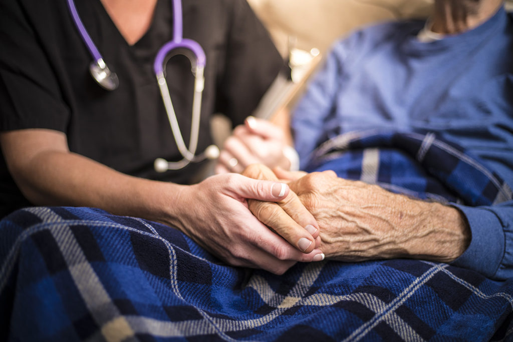 Clos up of nurse holding hands of an elderly patient with Parkinson's disease