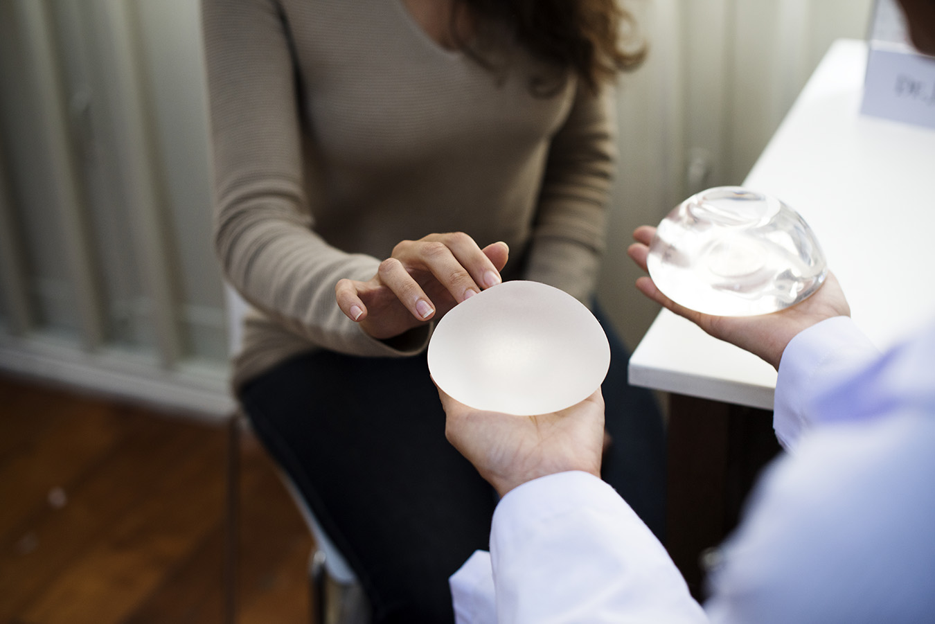 Woman looks at breast implant model at doctor's office