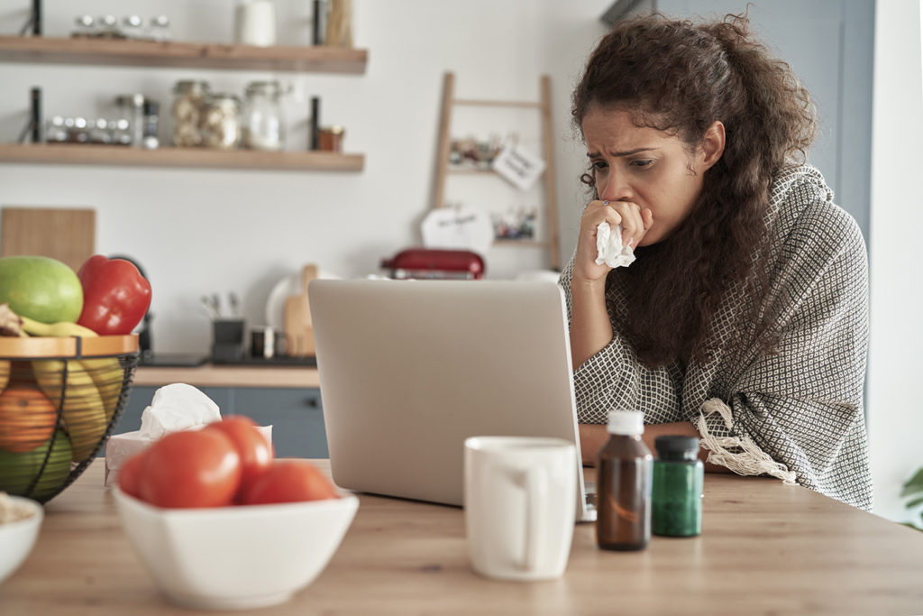 Sick woman using laptop at home