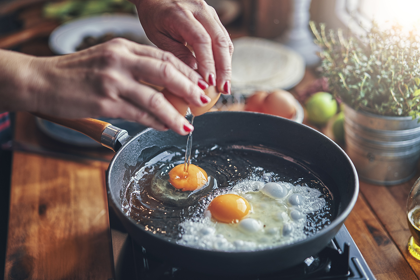 Hands breaking iron-rich eggs into skillet