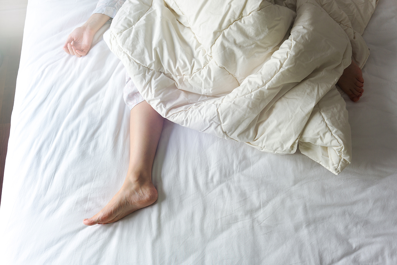 Photo of legs splayed on mattress during restless sleep