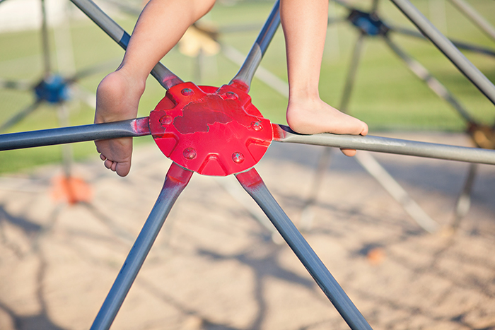 Kid's Feet Climbing a Geometric Dome At The Playground