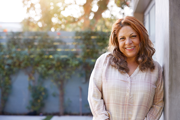 Senior Hispanic woman smiling as she leans outside