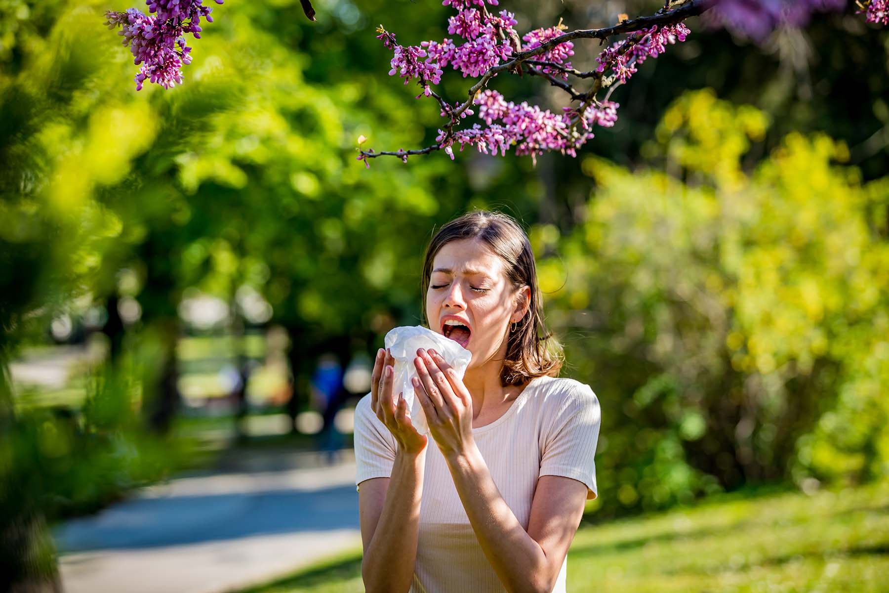 Woman sneezing outside pollen