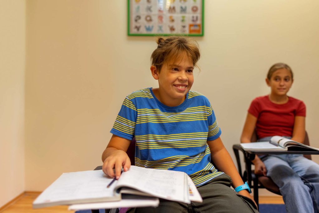 Boy student with cochlear implant smiles in class