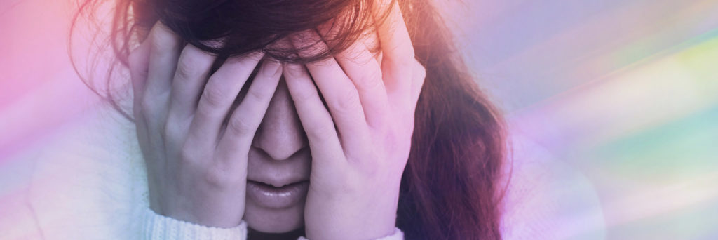 Woman with migraine aura holding head in pain.
