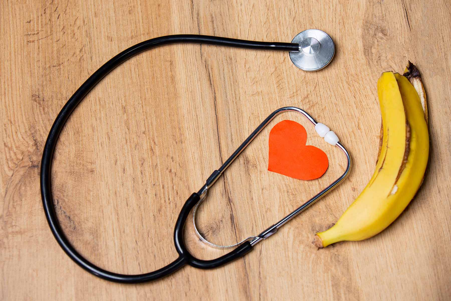 Stethoscope and heart cutout with banana on wood backdrop