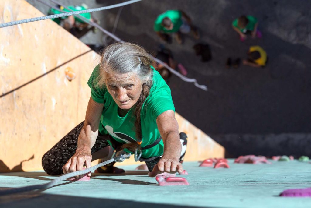 Elder woman doing wall climb exercise. Super ager