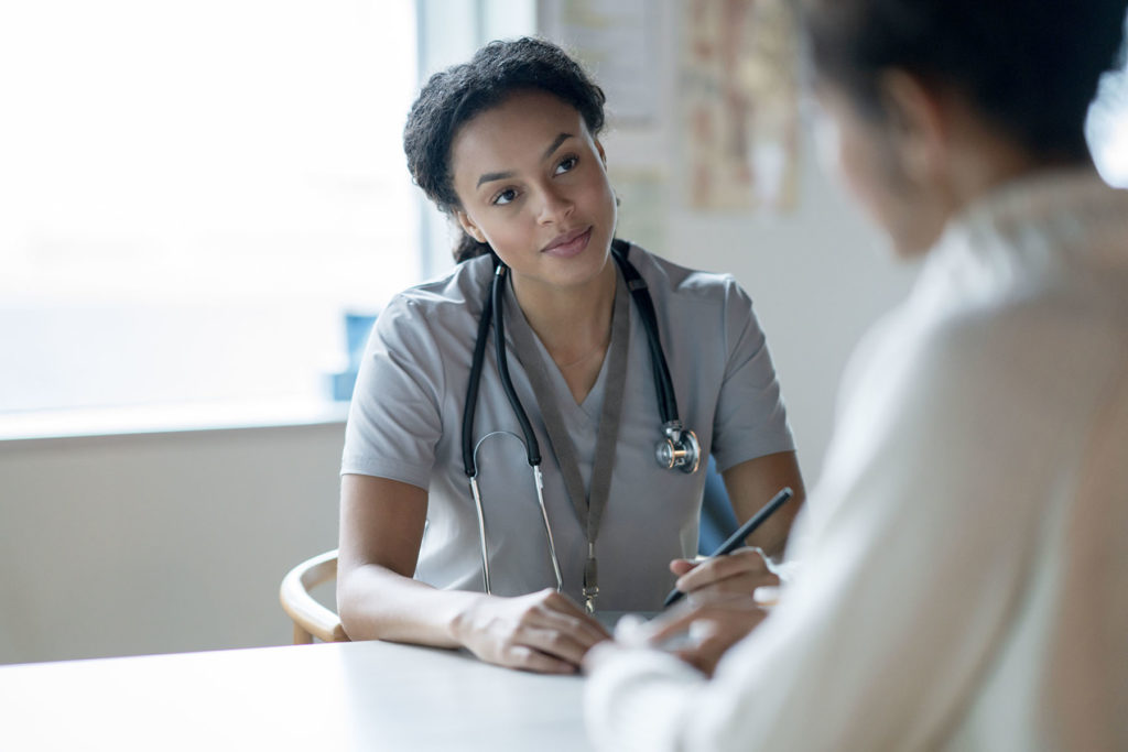 Advanced Practice Providers, also known as NPs or PAs, offer high-level expertise. here a Black female APP helps patient.
