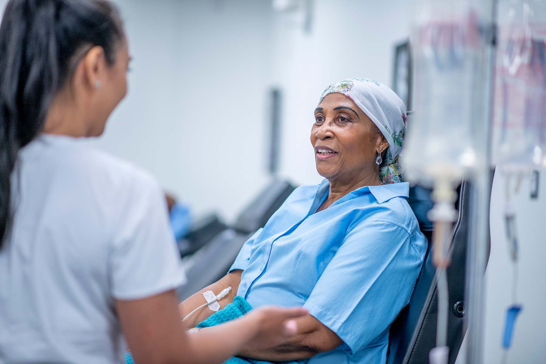 Nurse speaks to Black female patient receiving chemotherapy.