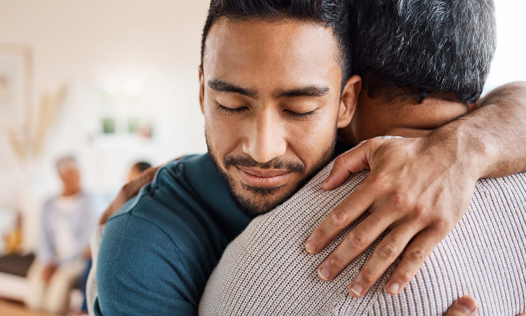 Young Hispanic man hugs an older man, possibly his father