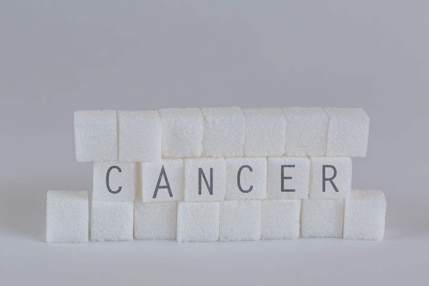 Image of stacked sugar cubes with cancer written on them.
