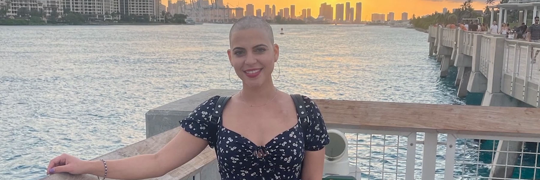Smiling woman with shaved head with the Miami waterway and sunset in the background