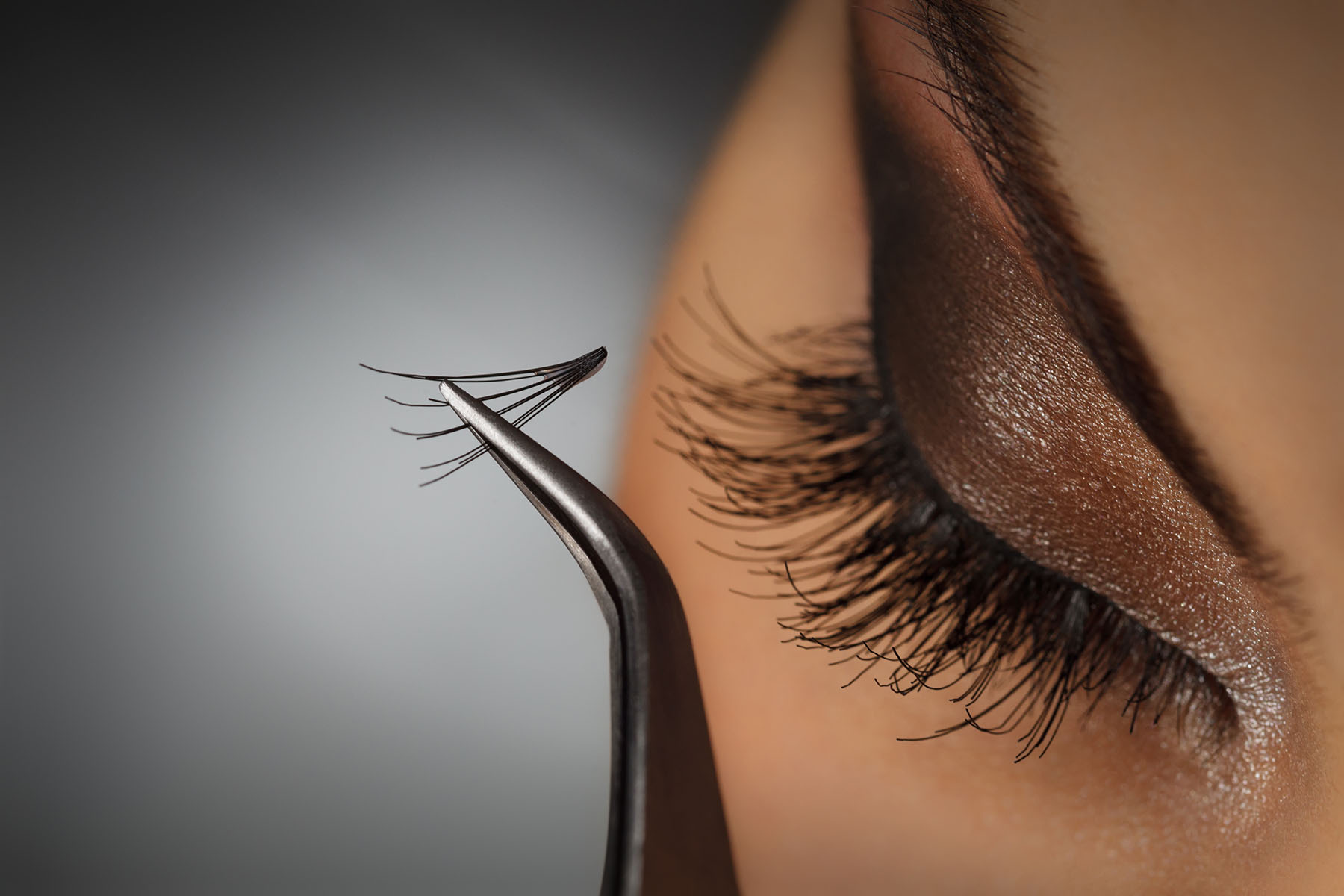 Close up of a woman putting eyelash extensions on.
