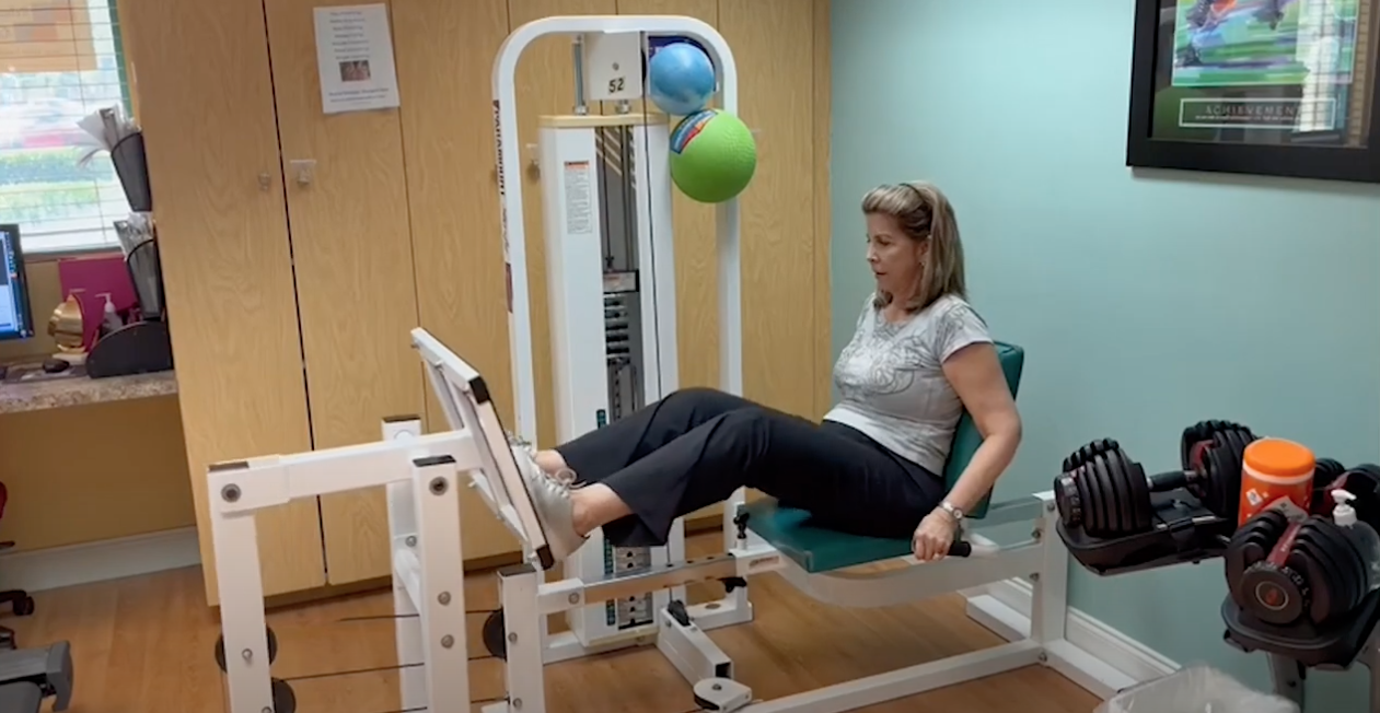 Female patient uses training equipment while recovering from joint surgery.