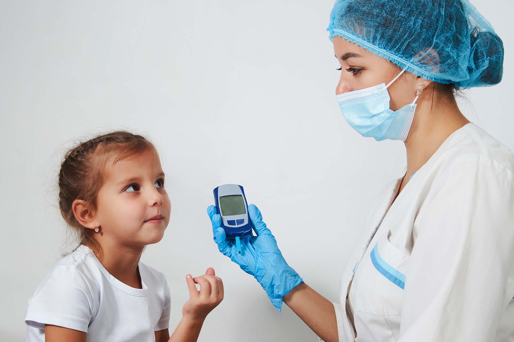 Nurse checks blood sugar of a little girl with diabetes.