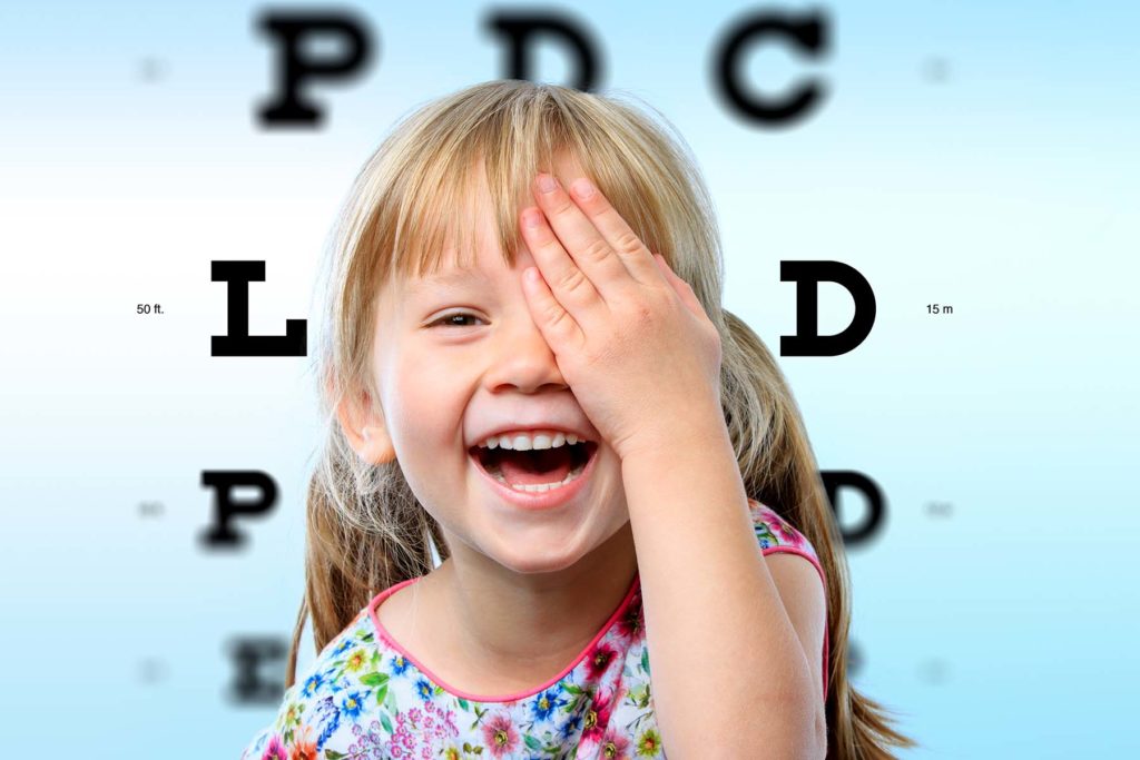 Cute little blonde girl giggles and covers her eye during eye exam.