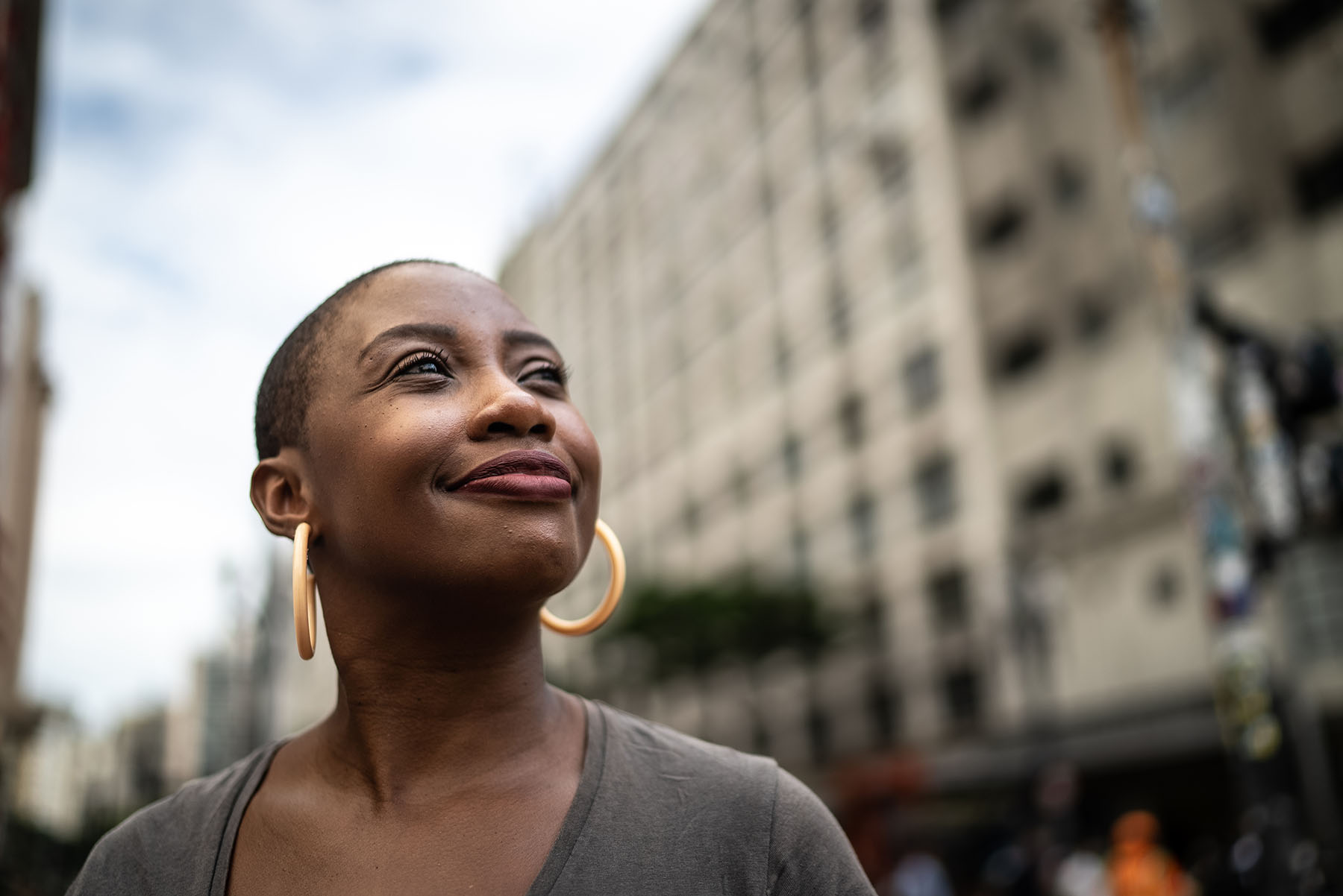 Pretty Black woman standing on city street, smiles.