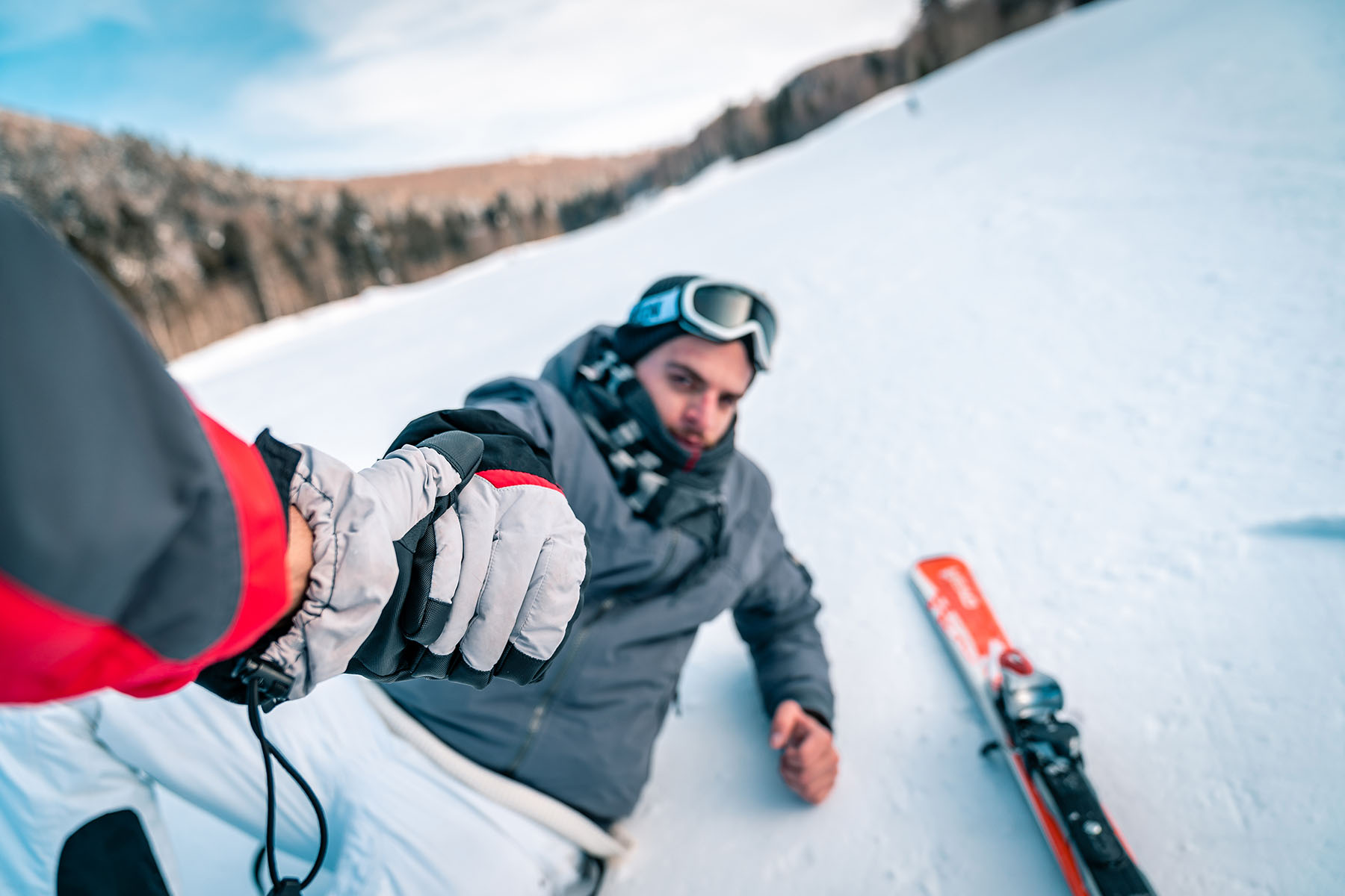 Skier fell and is being helped up friend.