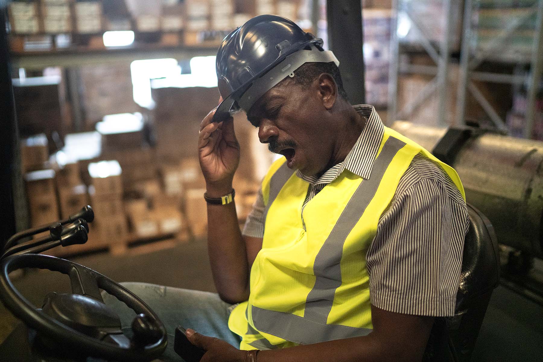 Black factory worker yawns while operator crane lift.