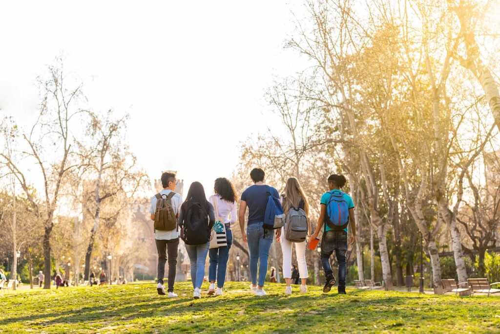 A group of young adults walking away toward a college building, signaling independence.