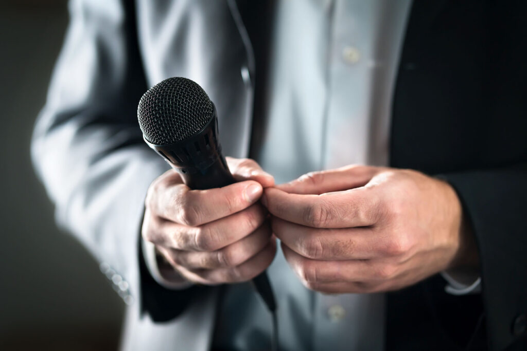 Close up of businessman's jittery hands holding microphone.