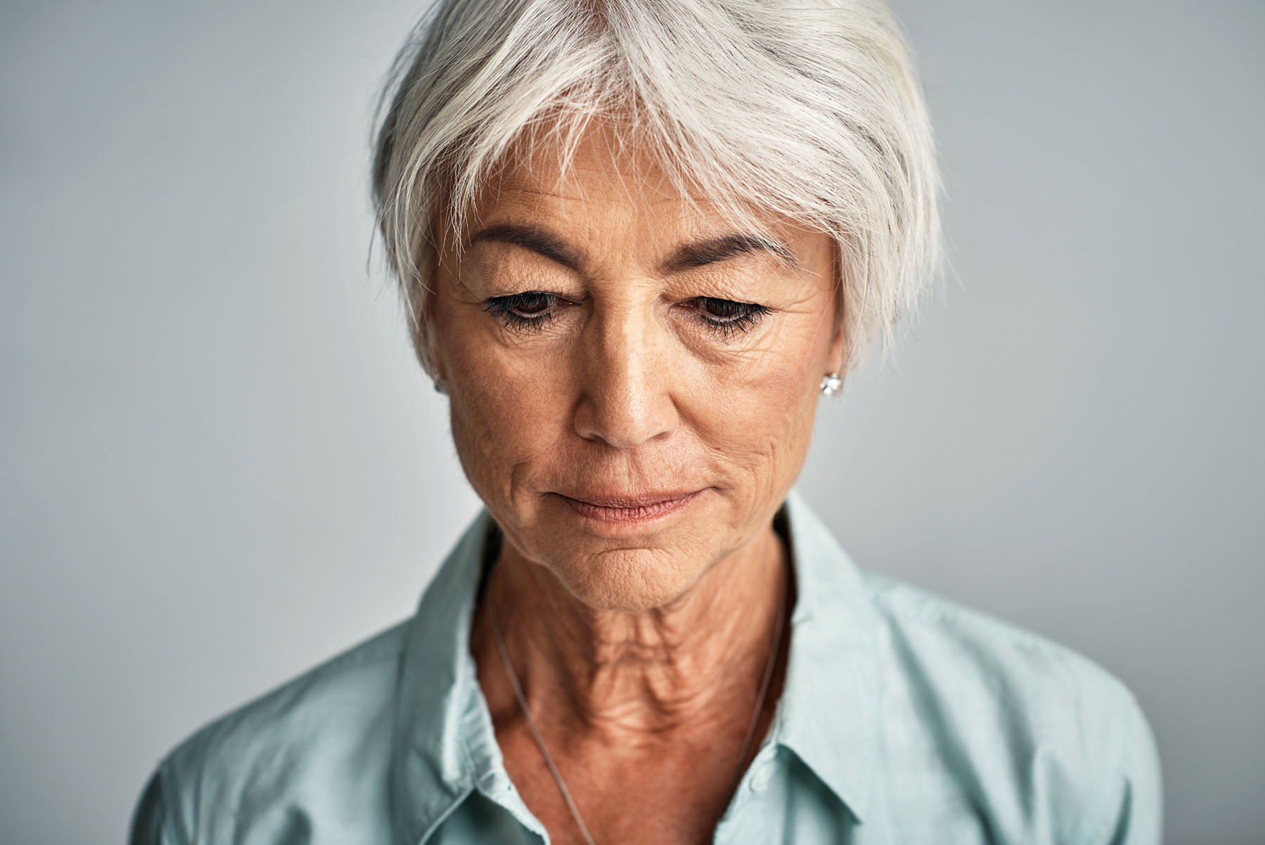 Close up portrait of sad, attractive older Hispanic woman questioning the future.