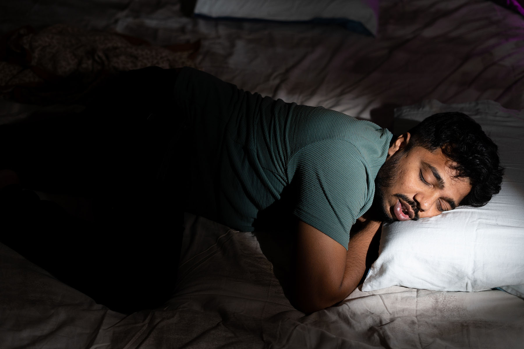 Young Black man enjoying goos quality sleep in a darkened room.
