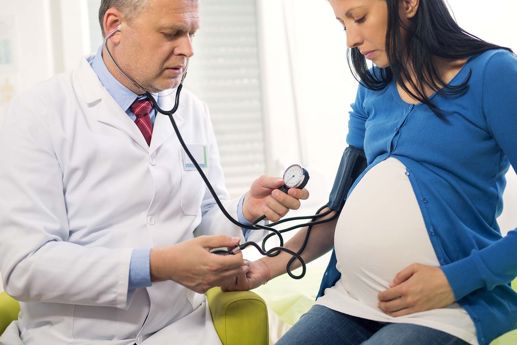 Pregnant woman gets her blood pressure checked at doctor appointment to check for preclampsia.